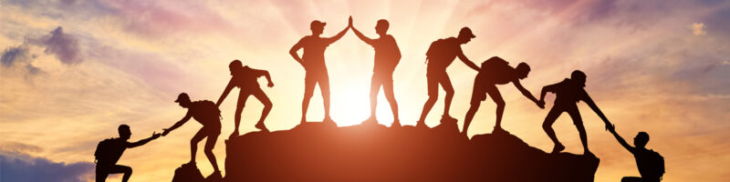 silhouette climbers at mountain summit